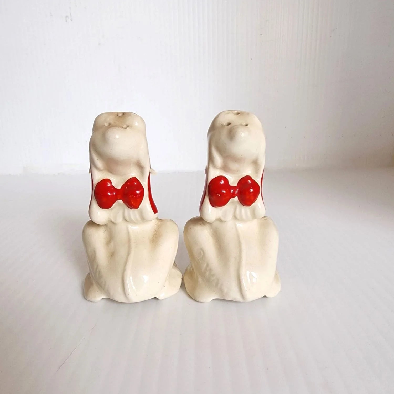 Pair of ceramic dog figurines with red noses, one seated and one standing, perfect for holiday decor.
